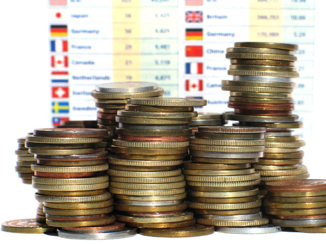kopa mincí stojící před kurzy měn